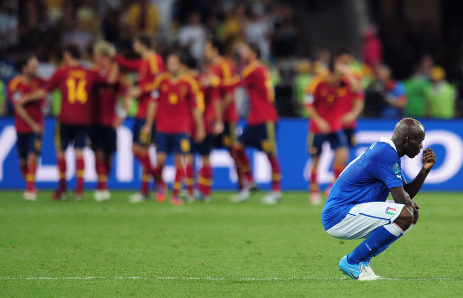 Mario Balotelli of Italy shows his dejection as the the Spanish team celebrate