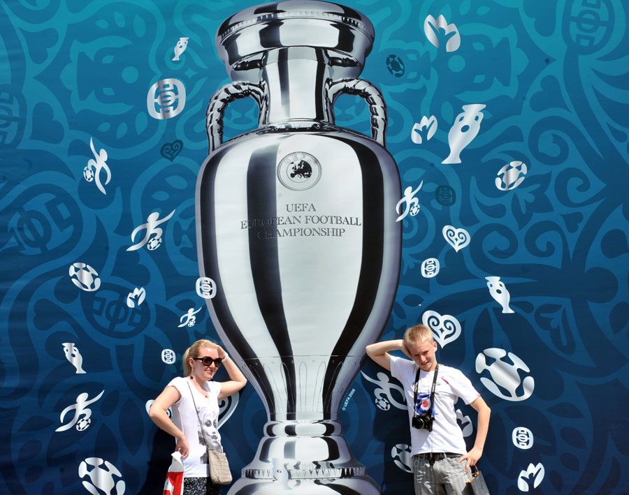 Tourists pose for a picture in front of Euro 2012 cup placard