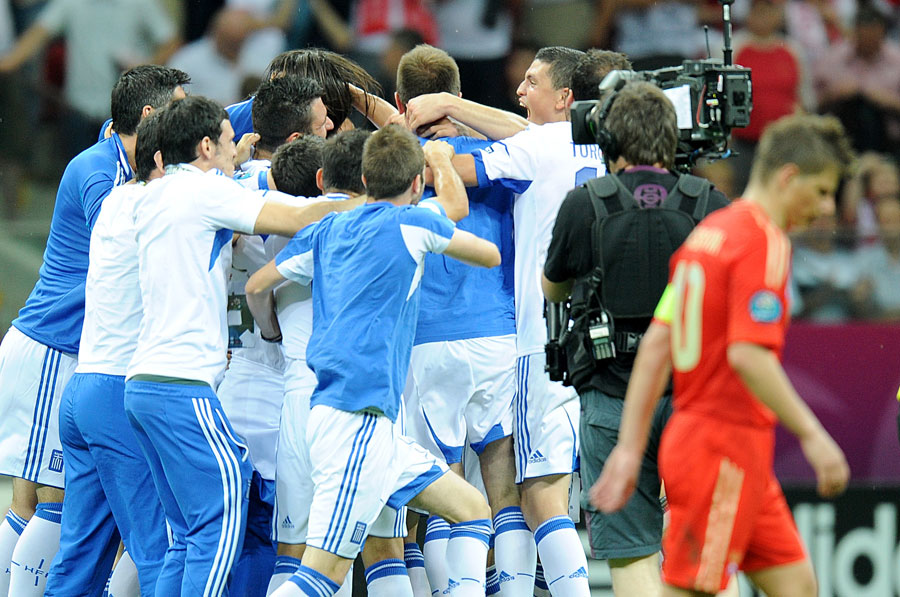 Russia's Andrey Arshavin leaves the field of play dejected after the final whistle, as Greece players and staff celebrate in the background