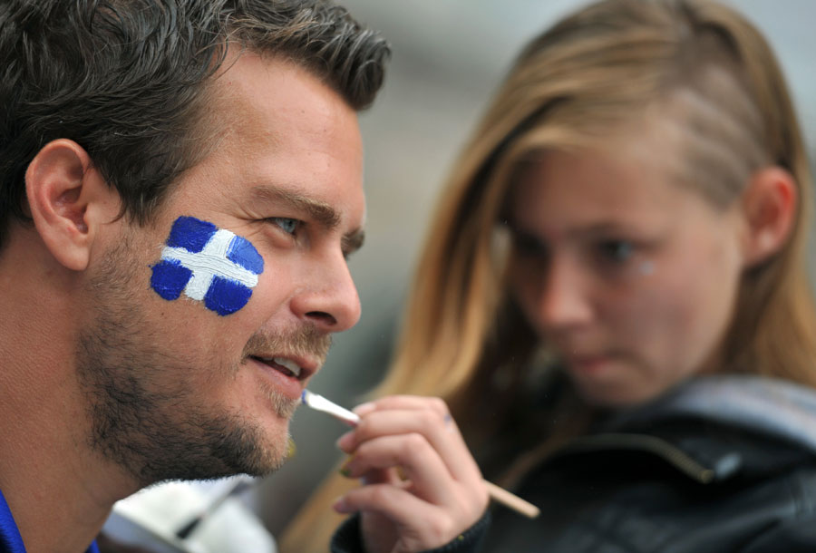 A supporter of Greece gets his face painted in the national colours prior to the game