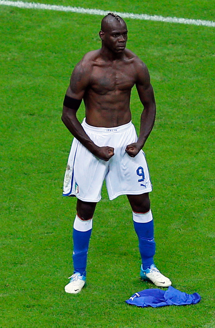 Italy's Mario Balotelli celebrates and earns himself a booking for taking off his shirt